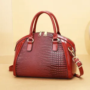Sac à main rouge en cuir verni gaufré croco avec anses doubles et bandoulière amovible.