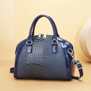 Vue détaillée du sac à main en cuir verni bleu foncé avec motif crocodile et détails dorés.