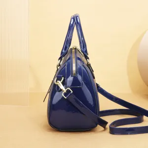 Vue latérale détaillée du sac à main en cuir verni bleu brillant avec fermeture éclair et poignées.