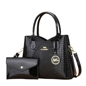 Set di borsa a mano in pelle verniciata nera con motivo coccodrillo e dettagli dorati.