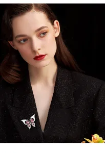 Detailed view of an elegant crystal zircon butterfly brooch worn on a classic black coat.