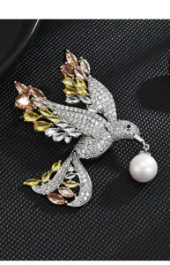 Elegant gradient crystal bird brooch detail shot featuring sparkling rhinestones and a hanging pearl.