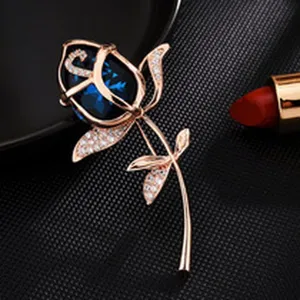 Exquisite rose brooch featuring a stunning deep blue crystal and sparkling rhinestone accents in rose gold.