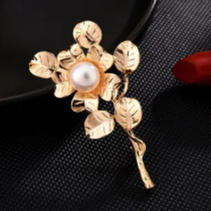 Close-up detail of an elegant gold flower brooch featuring a central white pearl design.