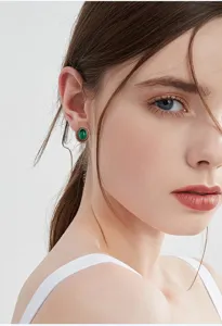 Detalle en primer plano de elegantes pendientes de botón ovalados con gema verde vintage.