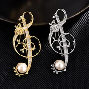 Detailed view of elegant musical note brooch with pearls and rhinestones in gold and silver.