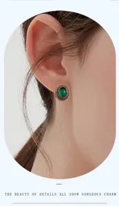 Vista de cerca de elegantes pendientes ovalados verdes con un halo de piedras rojas brillantes.
