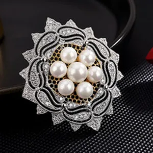 Elegant pearl and crystal floral brooch detail, intricate silver and black design.