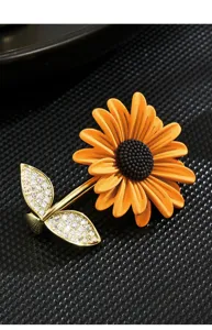 Close-up detail of a delicate dripping oil sunflower brooch with rhinestone leaves on black pad.