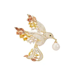 Exquisite gradient cubic zirconia bird brooch with elegant pearl, luxury gold-toned jewelry.