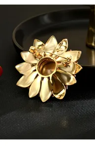 Gedetailleerde close-up van de gouden bloemenbroche achterkant met speld en gepolijst metaal.