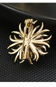 Gold crystal snowflake brooch detail view showing secure pin clasp and metallic back structure.