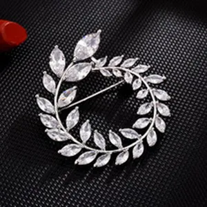 Close-up detail shot of exquisite cubic zirconia leaf wreath brooch, shiny silver metal.