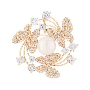Close-up detail of gold butterfly brooch with micro-inlaid zircons and central pearl accent.