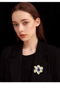 Elegant flower magnetic brooch with sparkling stones and blue center for shirts.