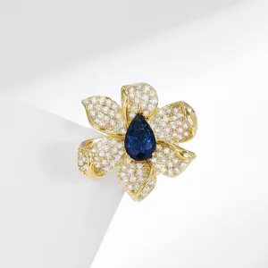 Exquisite floral magnetic brooch with sparkling pavé stones and blue gemstone center on main display