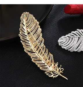 Elegant gold and silver feather brooch pins with sparkling rhinestones for women fashion.