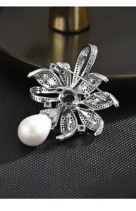 Detailed reverse view of silver floral brooch featuring sparkling rhinestones and white pearl.