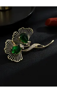 Elegant ginkgo leaf brooch featuring emerald green crystals and sparkling clear rhinestones.
