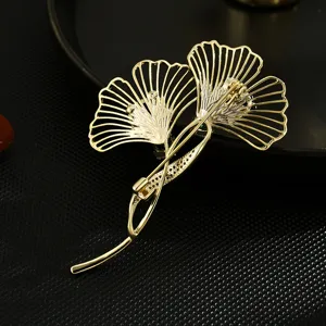 Elegant ginkgo leaf brooch with green crystal inlay, gold tone metal fashion pin accessory.
