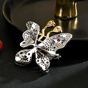 Elegante Schmetterlingsbrosche mit roten und weißen Zirkoniasteinen im luxuriösen Bicolor-Design.