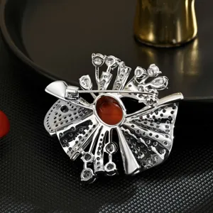 Broche géométrique argentée avec zircone cubique et pierre centrale pour manteau.