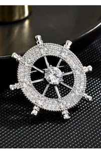 Close-up detail of silver ship wheel brooch with micro-paved zirconia and central stone.