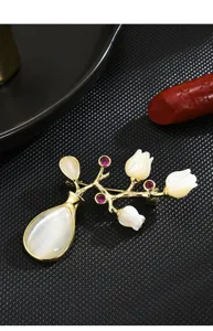 Close-up detail of vintage style vase flower brooch with mother of pearl and cat eye stones.