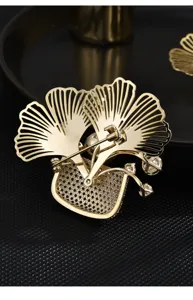 Close-up detail of gold-plated ginkgo leaf brooch back structure and sparkling paved cubic zirconia.