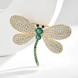 Elegant dragonfly brooch with sparkling white zirconia and green crystal gemstones.