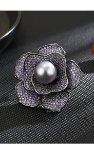 Close-up detail of luxury purple cubic zirconia flower brooch with a central grey pearl.