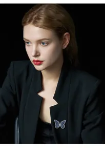 Gros plan détaillé d'une broche papillon en strass bleu vintage portée sur une veste noire.
