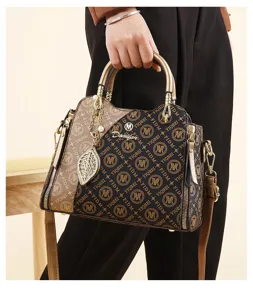 Vue détaillée du sac à main colorblock élégant avec pendentif feuille et détails métalliques.