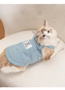 Detailed shot of a cute cat wearing a light blue denim pet suspender dress with pocket.