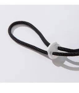 Vue détaillée du cordon de serrage tissé noir réglable et du stopper blanc pour chapeau.