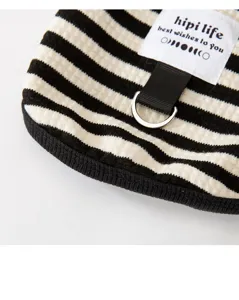 Close-up detail of black and white striped pet clothes with a D-ring and brand label.