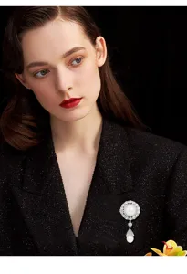 Close-up detail of vintage court style pearl and zirconia brooch on elegant black jacket.