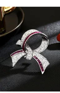 Elegant ribbon brooch with sparkling cubic zirconia and ruby-colored stones for women.