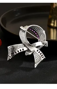 Detailed close-up of a silver-toned pavé crystal and purple stone ribbon brooch jewelry.