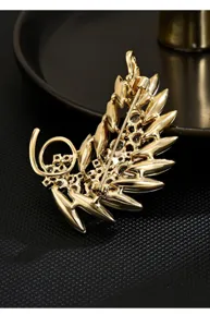Gold crystal feather brooch, elegant suit pin accessory for women, fashion jewelry detail view.