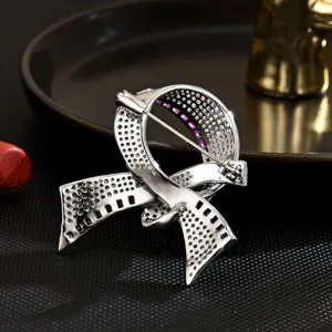 Elegant silver ribbon brooch with sparkling crystal and purple stone details for coats.