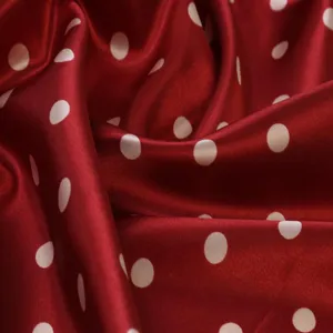 Close-up view of the smooth red satin fabric featuring classic white polka dots texture details.