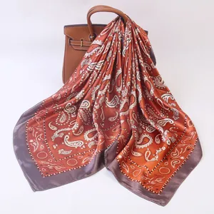 Detailed view of orange silk paisley scarf draped on luxury leather bag background elegance.