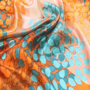 Detailed view of luxury silk square scarf with vibrant orange and blue abstract print texture.
