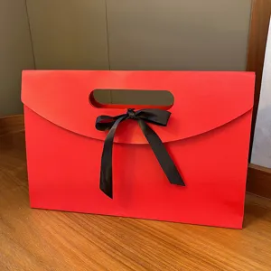 Red envelope gift box detail, elegant paper packaging with black ribbon bow for silk scarves.
