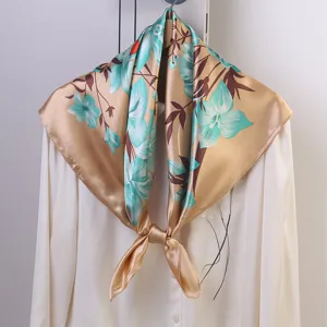Elegant floral silk satin square scarf detail showcasing vibrant teal blooms on gold.