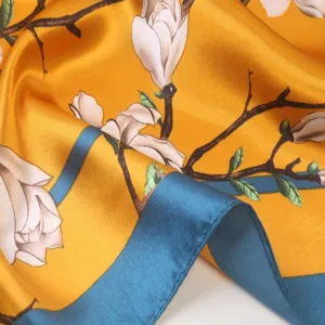 Luxury silk square scarf featuring elegant magnolia floral print and vibrant blue border.