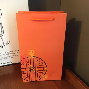 Orange paper gift bag with oriental design, perfect for silk scarves and holiday gifts.