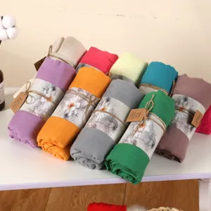 Detail view of rolled cotton linen scarves in assorted colors, showing texture and packaging details.