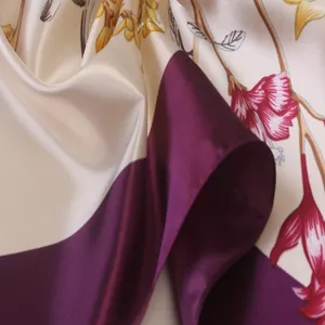 Close-up of satin silk scarf featuring vibrant floral prints and elegant purple color block.